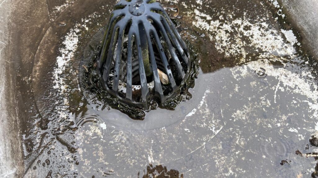 泥とゴミで排水口が覆われており、雨水の流れが妨げられています。