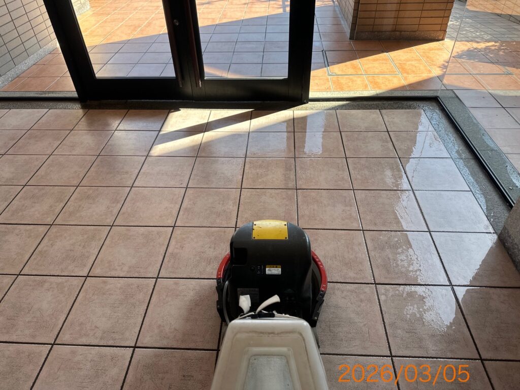 エントランスのタイル床をポリッシャー（床洗浄機）で磨き上げている様子