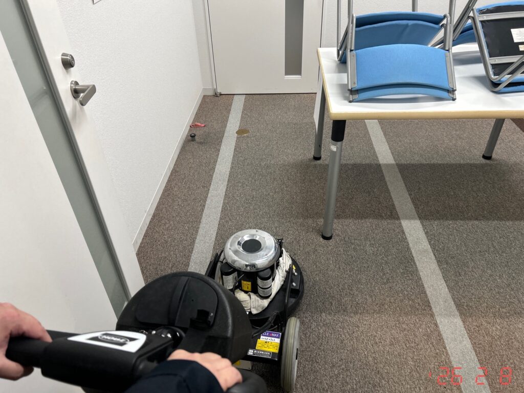 教室・会議室エリアにて、机や椅子を移動させながら床の汚れを機械で落としている様子