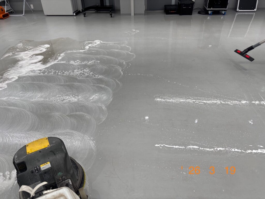 ポリッシャーと呼ばれる機械を使用し、リノリウムの床一面を泡立てながら洗浄している様子
