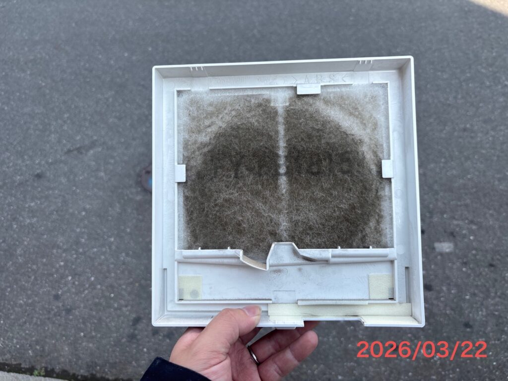換気扇のフィルターに、向こう側が見えないほどびっしりと分厚く付着したホコリ