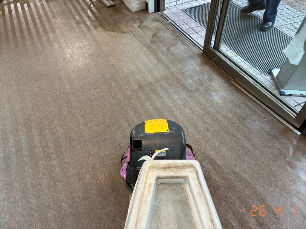 床用ポリッシャーを巧みに操り、廊下の古い汚れを丁寧に洗い落としている作業風景