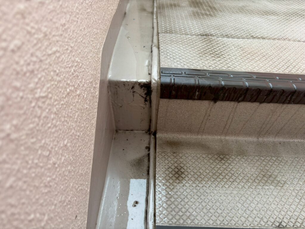 マンション外階段の隅の清掃前後比較。清掃前は土砂と苔が混ざった黒い汚れがこびりついている