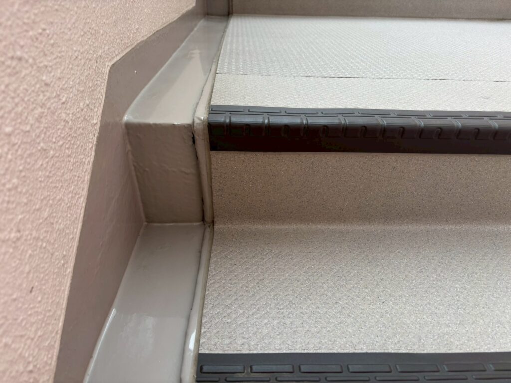 マンション外階段の隅の清掃前後比較。右の清掃後は汚れが完全に除去され、本来の明るい色とコーキングの白さが現れている