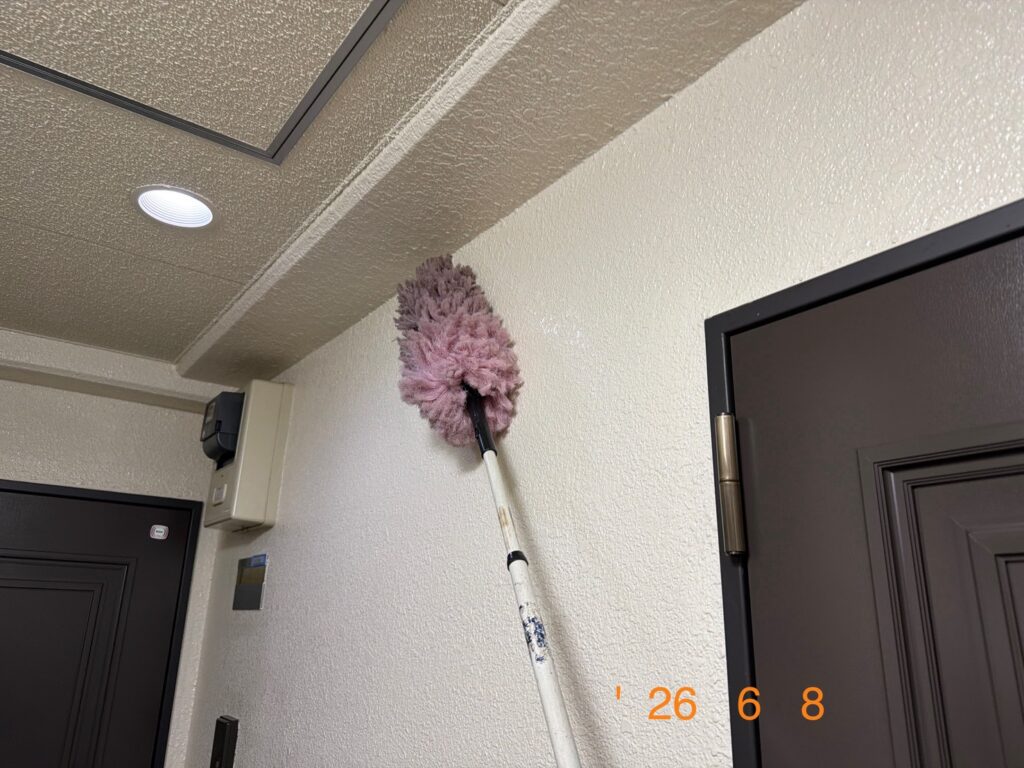 高所用の専用モップを使い、壁面や天井付近のホコリを落としている様子