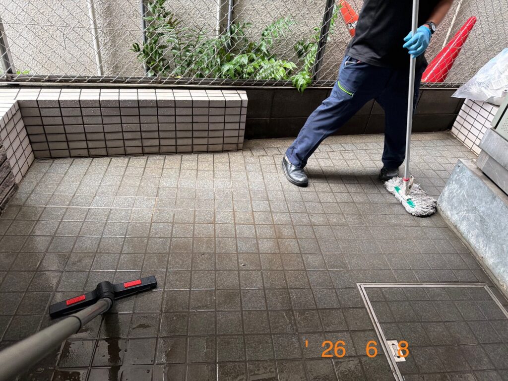 エントランスのタイル床を専用機材とモップで洗浄している様子