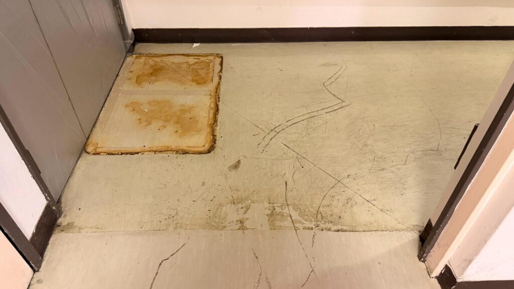 クリニックの床の一角。ワックスがくすみ、茶色い汚れの跡や擦り傷が広がっている作業前の状態