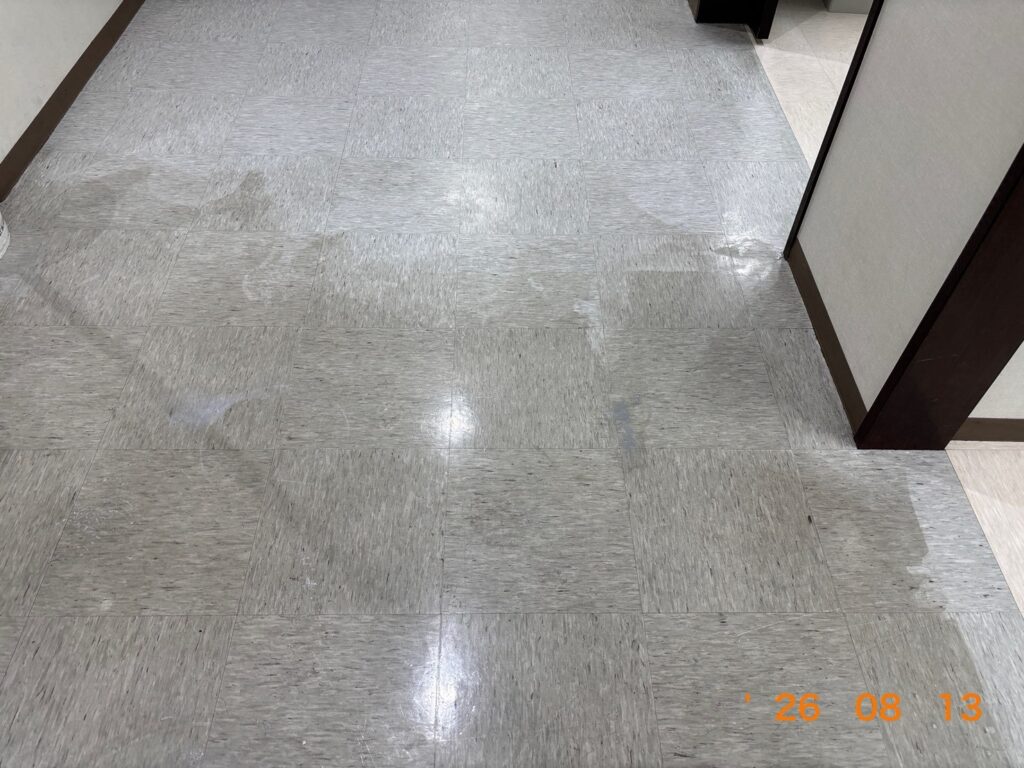 作業前の床タイル。ワックスが黄ばんでくすみ、白く曇った汚れが広がっている状態。