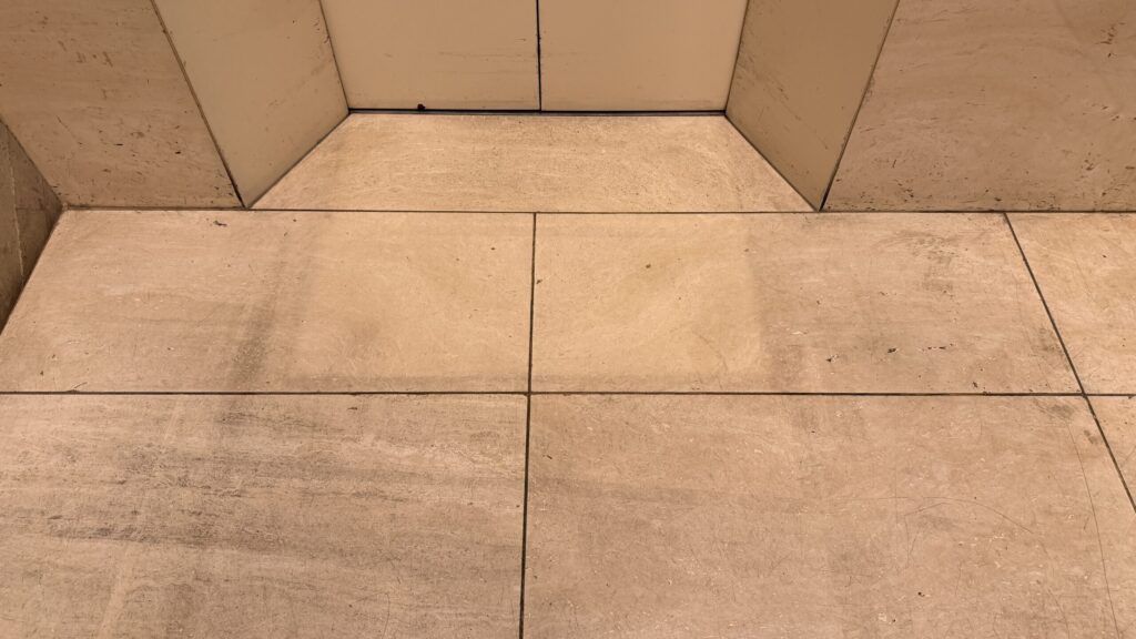 エントランスの大理石床。全体がくすみ、細かい傷で白茶けて曇った作業前の状態。