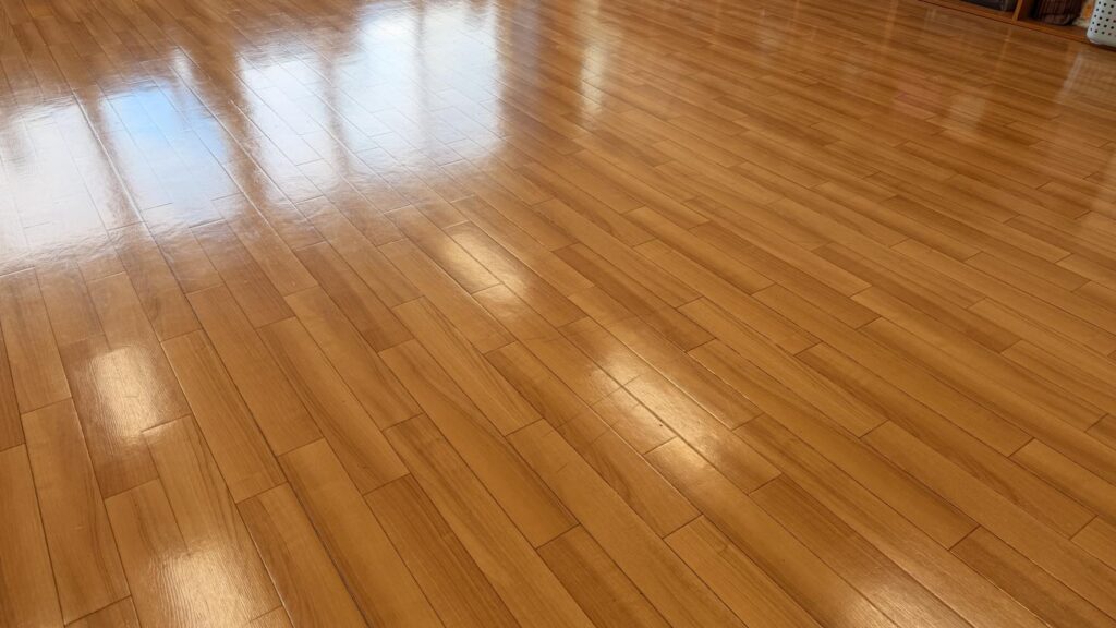 木目調の床。落ち着いた自然な艶が均一に出て、照明がやわらかく反射している。
